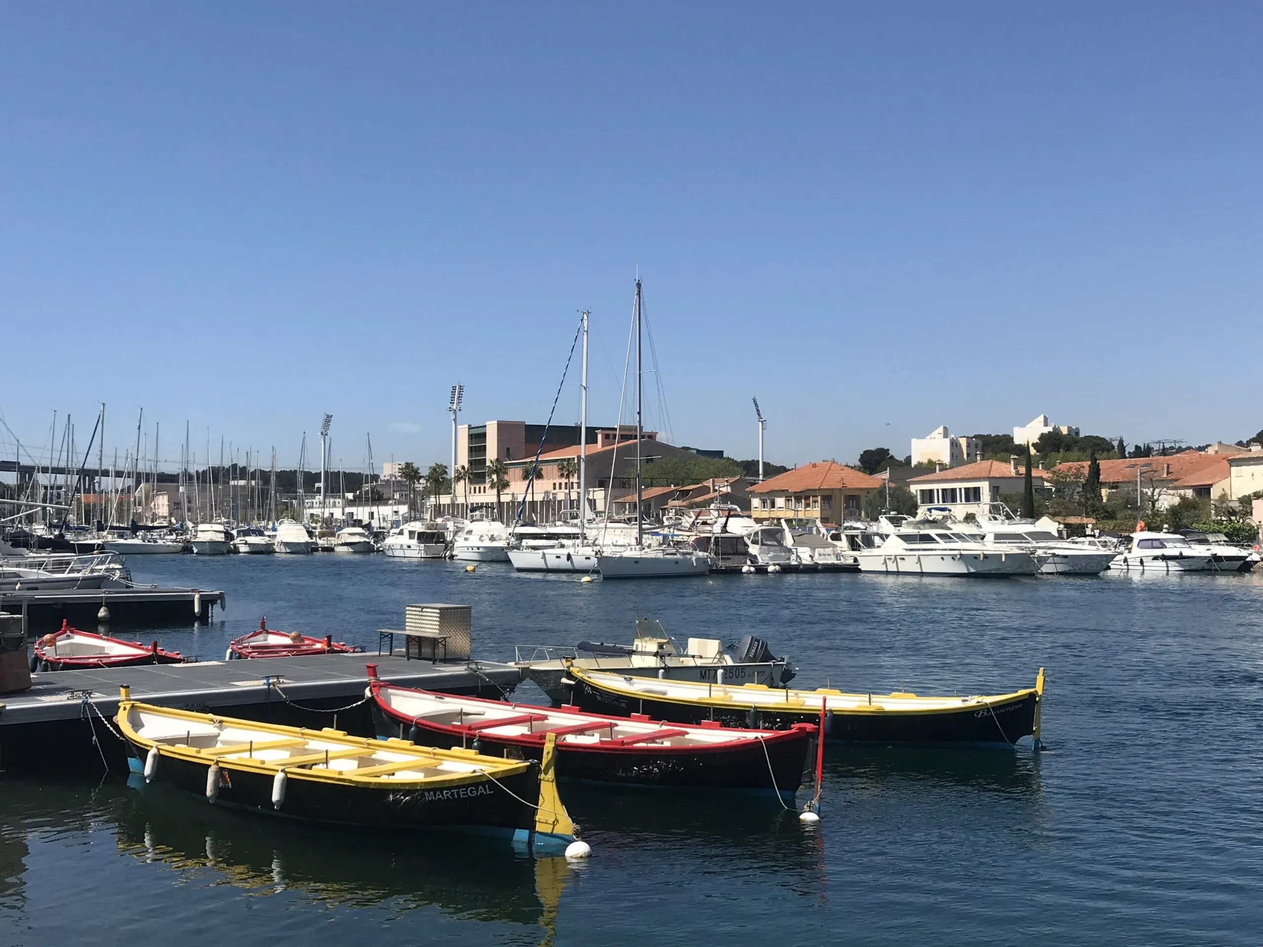 Dans les canaux de Martigues, même les barques sont aux couleurs de la Provence. En arrière-plan, on aperçoit le stade Turcan.