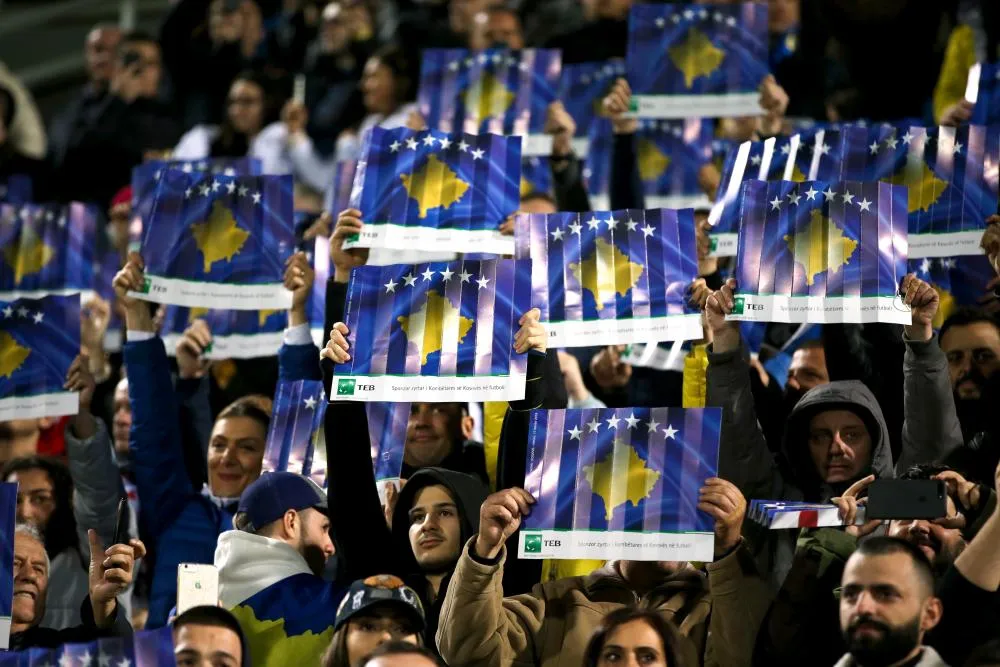 Les supporters du Kosovo chantent dans un haut-parleur aux abords du stade
