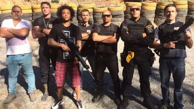 Photo : Marcelo pose avec une arme