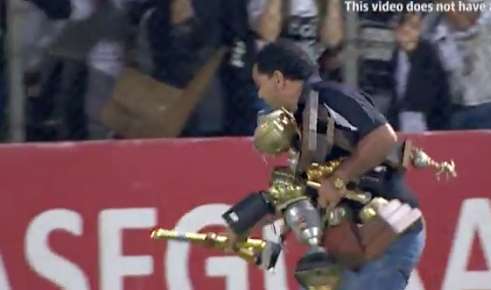 Des fans balancent les trophées du rival sur la pelouse